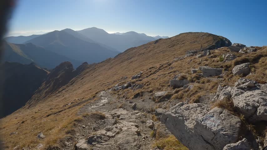 Hiker perspective follows a narrow rocky path along the return ridge toward Ciemniak under clear autumn sky