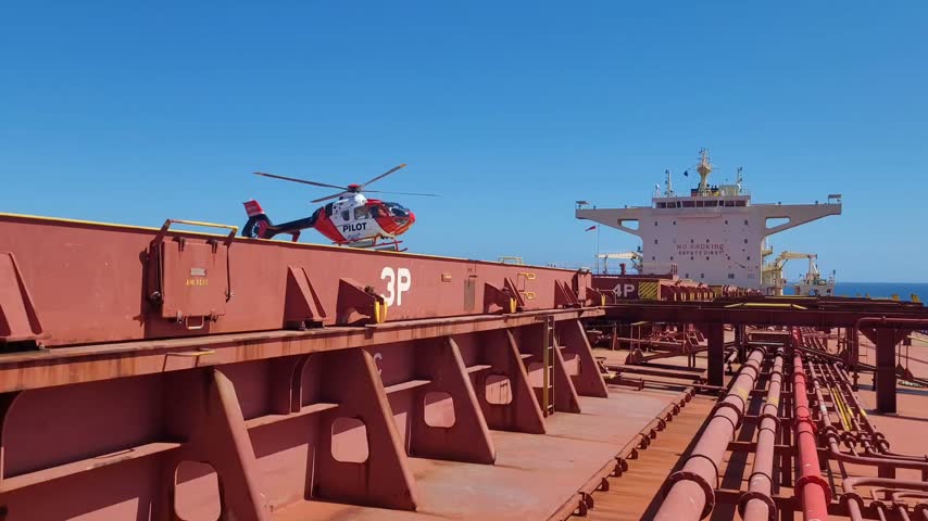 
Marine pilot helicopter approaching to land on cargo hatch number 4 to assist vessel berthing at Gladstone Port, Queensland Australia. Helicopter pilot transfer operation for bulk carrier
