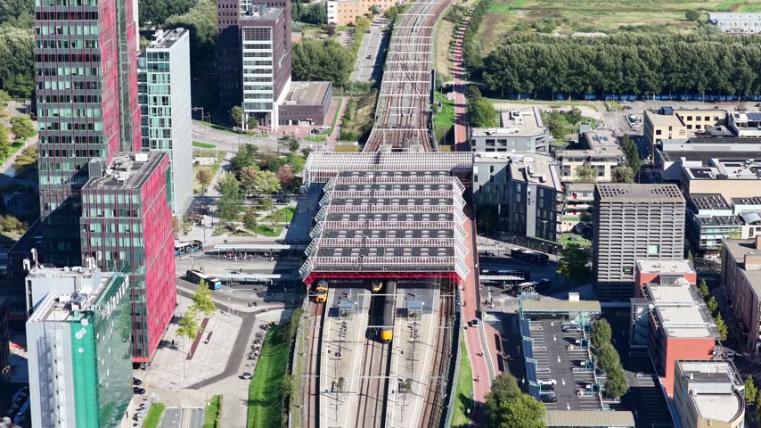 Aerial view of Almere Central Station in Flevoland, the Netherlands, surrounded by modern residential and commercial buildings in the city center.