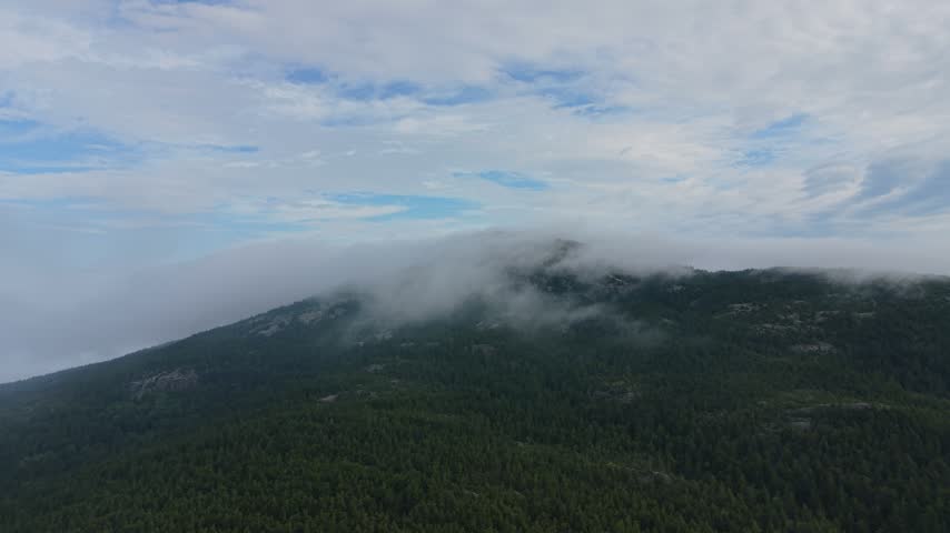 Epic aerial view ascending over Mount Monadnock with low clouds and a colorful sky during the morning