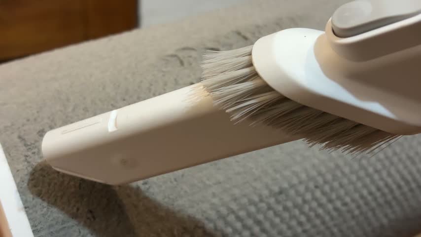 Cleaning thick dust and lint from a dirty cylindrical air purifier filter with a vacuum cleaner brush attachment