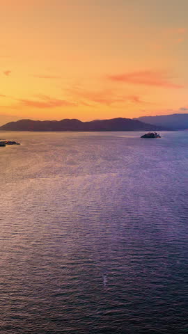 San Francisco bay waters at sunset, California. Calm ocean surface with distant dark hills and colorful gradient sunset sky. Vertical video.