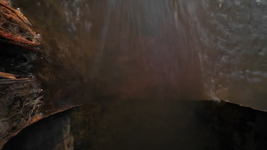 Flowing water cascading down dark rocky stream