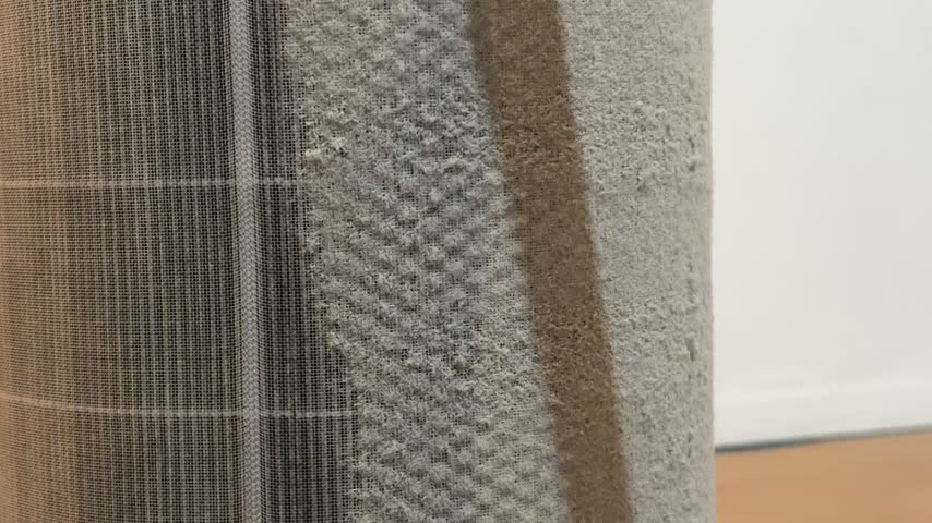 Cleaning thick dust and lint from a dirty cylindrical air purifier filter with a vacuum cleaner brush attachment