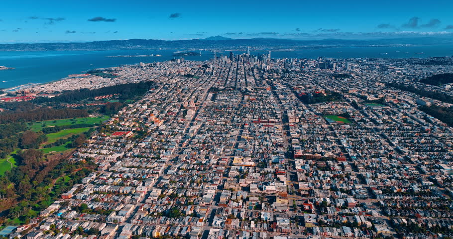 Dense urban landscape with low-rise architecture. Sunny panorama of San Francisco, California, USA. Skyscrapers of downtown and bay waterscape at backdrop. Aerial view.