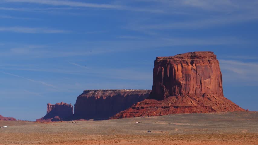Famous red sandstone buttes in Monument Valley, located on the border between Arizona and Utah, USA, within the territory of the Navajo Nation. Massive mesas and sandstone buttes composed of the Kayenta and Moenkopi formations, displaying their characteristic deep reddish color due to iron oxides.