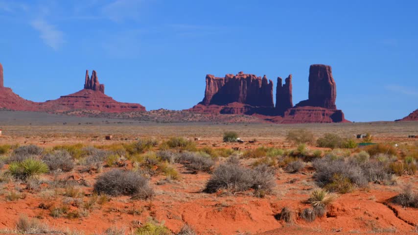 Monument Valley is a famous geological park located on the border between Arizona and Utah, USA, within the Navajo Nation Reservation. On the left, the characteristic mitten-shaped sandstone buttes are visible, probably West Mitten Butte and East Mitten Butte. In the background, extensive flat-topped red sandstone mesas rise above the desert landscape, forming an iconic symbol of the American Wild West.