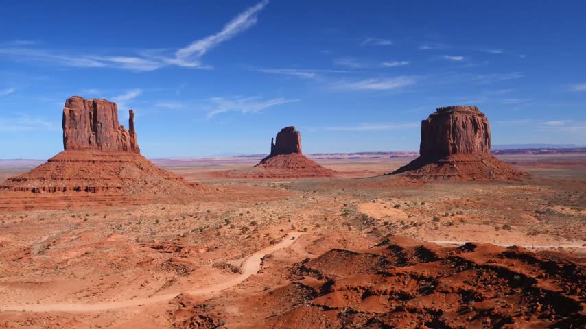 Monument Valley, located on the border of Arizona and Utah in the United States, within the Navajo Nation reservation. The foreground features famous sandstone buttes: West Mitten Butte on the left, Merrick Butte in the center, and East Mitten Butte on the right.