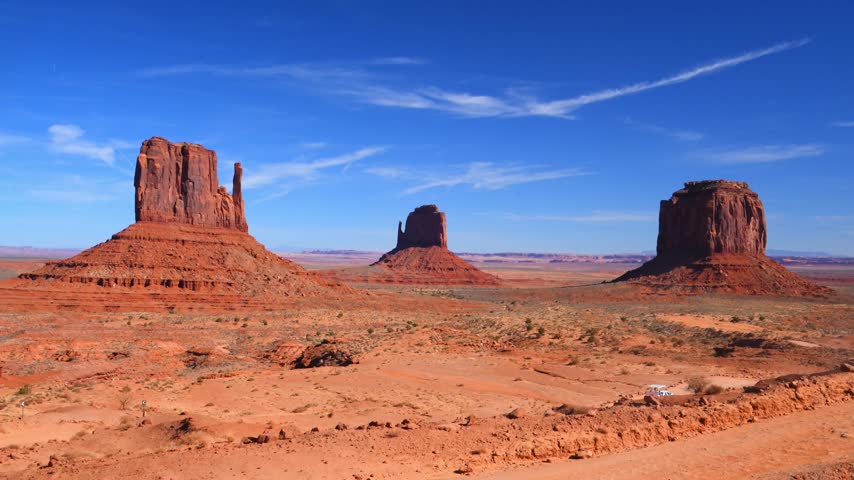 Monument Valley, located on the border of Arizona and Utah in the United States, within the Navajo Nation reservation. The foreground features famous sandstone buttes: West Mitten Butte on the left, Merrick Butte in the center, and East Mitten Butte on the right.