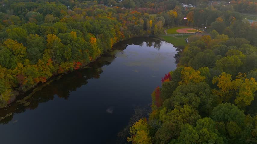 Autumn landscape at Stanley Quarter Park in Connecticut, USA, featuring colorful fall forest, calm water reflections, and soft evening light.