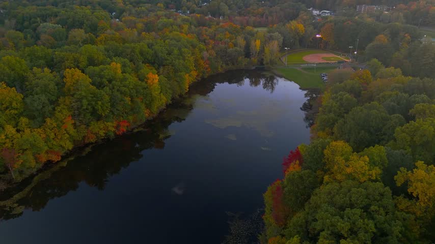 Scenic autumn landscape at Stanley Quarter Park in Connecticut, USA, featuring colorful fall forest, calm water reflections, and soft evening light. 4K.