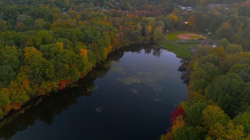 Autumn landscape at Stanley Quarter Park in Connecticut, USA, featuring colorful fall forest, calm water reflections, and soft evening light. 4K.