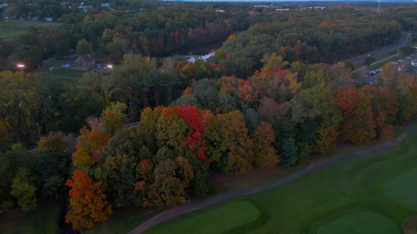 Scenic aerial view of Stanley Quarter Park in New Britain, Connecticut, showcasing autumn foliage, a reflective lake, and warm sunset colors.