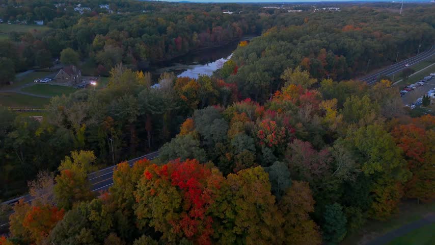 Fall landscape at Stanley Quarter Park, Connecticut, USA, with a peaceful lake surrounded by vibrant autumn trees during magic hour.