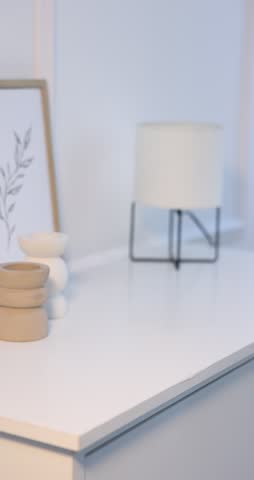 Woman putting glass vase with colorful roses onto cabinet indoors, closeup