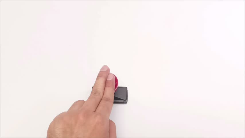 Close up view of a hand stamping a red ink rubber stamp onto a clean white paper surface during office paperwork.