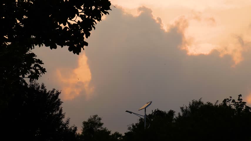 Autumn sunset light breaking through thick clouds over a park at dusk