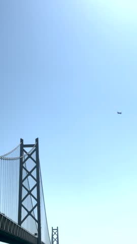 An Airplane Flying Above Bridge