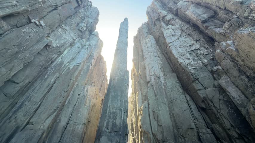 Looking up at the Totem Pole sea stack between towering cliffs.