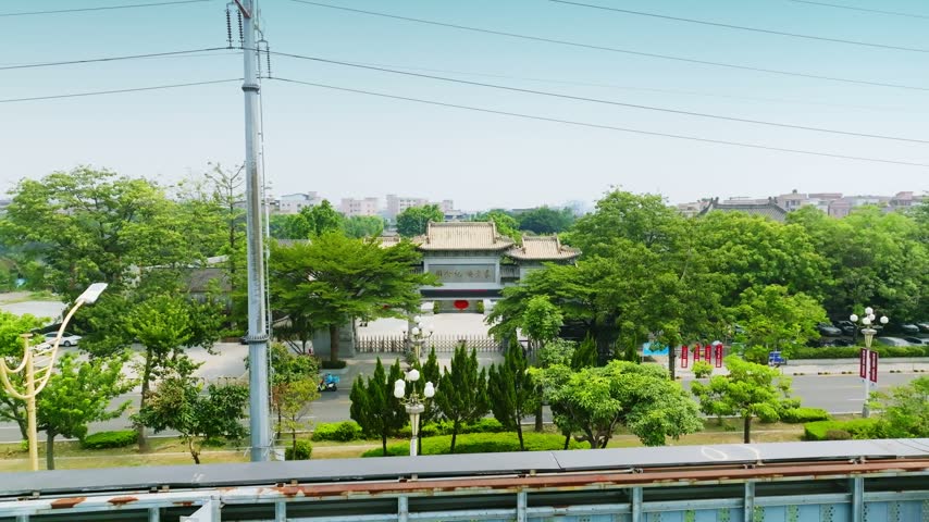 Aerial footage shows tree framed entrance arch to a memorial garden. Location: Yuan Chonghuan Memorial, Dongguan, Guangdong, China. In daylight, the view records the visible setting and subject details.