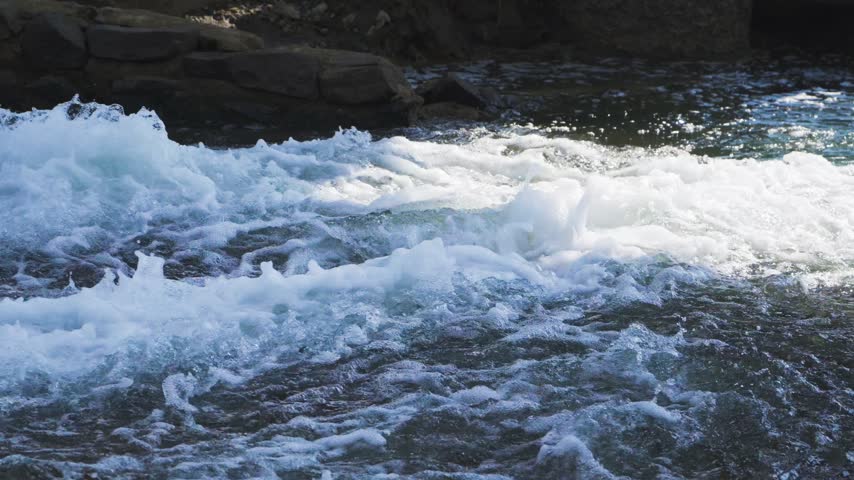 Polluted water flowing from a drainage pipe into a natural rocky stream environment