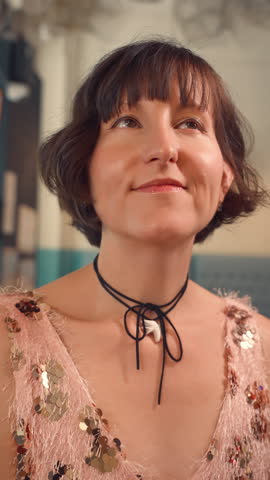 Woman resting her hand near her chin and looking upward with a slight smile in a cafe.