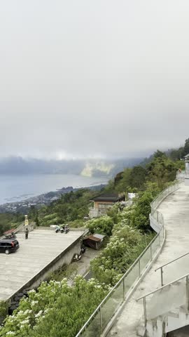 Overlook of Lake Batur under heavy cloud from Kintamani, Bali, tiny distant figures