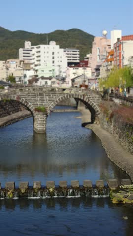 Meganebashi Spectacles Bridge, Megane bridge, stone double arch bridge over Nakashima river in Uonomachi, Nagasaki, Nagasaki Prefecture, Kyushu Island, Japan, buildings and green hills on a sunny day