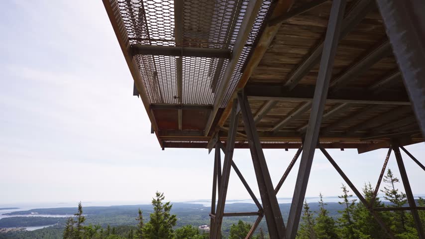 Expansive video overlooking lush green forests, islands, and coastal waters from the Beech Mountain fire tower in Acadia National Park, Maine.