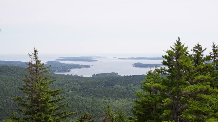 Panoramic view across dense evergreen forests toward coastal islands and the Atlantic Ocean from the summit of Beech Mountain in Acadia National Park on Mount Desert Island, Maine.