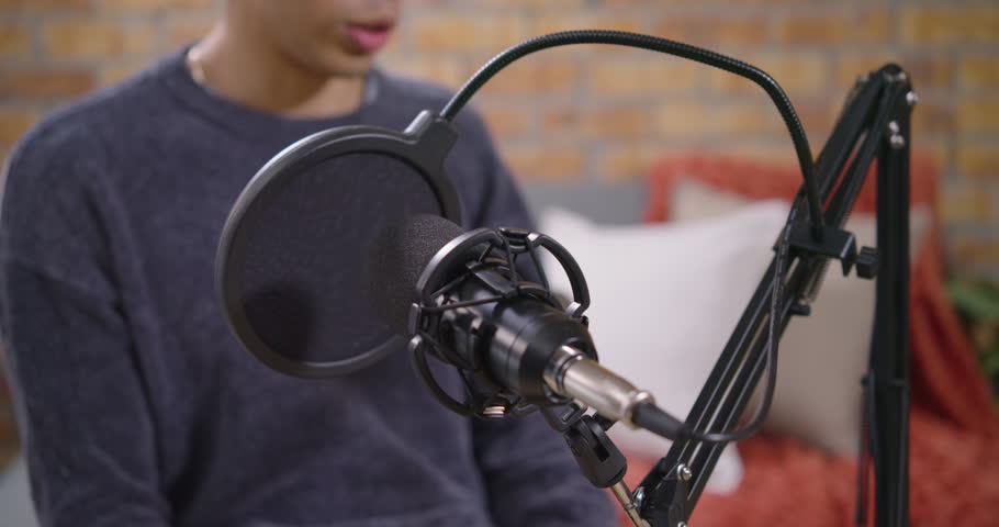Male host and female cohost responding to condenser mic focus, speaking and gesturing on set. Podcast, studio, duo, conversation, interview, cozy, brickwall