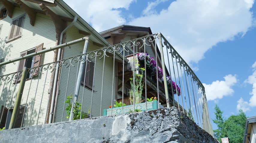 Low angle view of a beautiful swiss house with balconies decorated with flowers on a sunny day. Switzerland