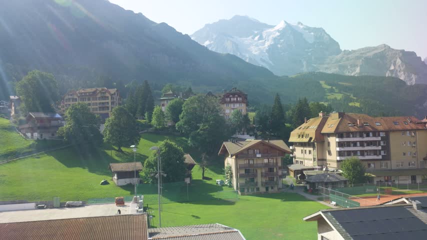 Picturesque alpine village of wengen nestled in a green valley beneath the snow-capped swiss alps. Switzerland
