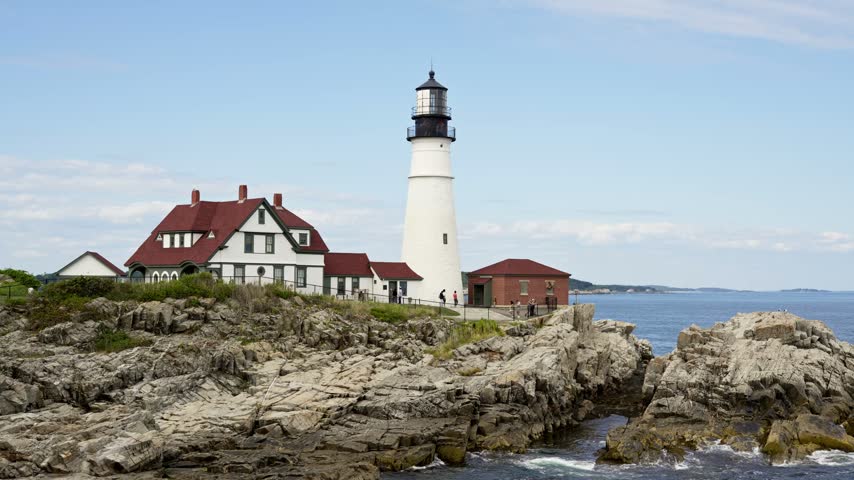 Cape Elizabeth, Maine- August 21st, 2026: Historic Portland Head Light standing proudly on rugged rocky shores in Cape Elizabeth, Maine, under a clear blue sky.