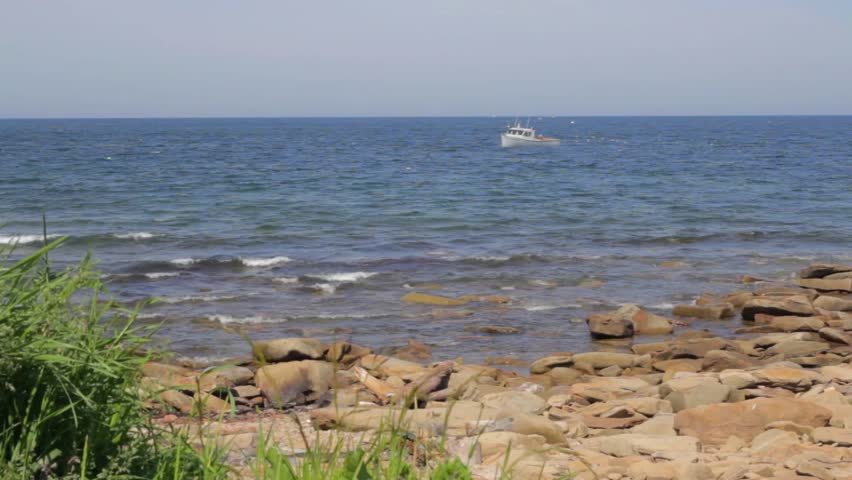A jib shot of a rocky ocean shoreline and fishing boat