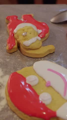 Colorful assortment of christmas-themed cookies, including santa claus and trees, being decorated with sweet icing and a variety of festive sprinkles on parchment paper during the holiday season