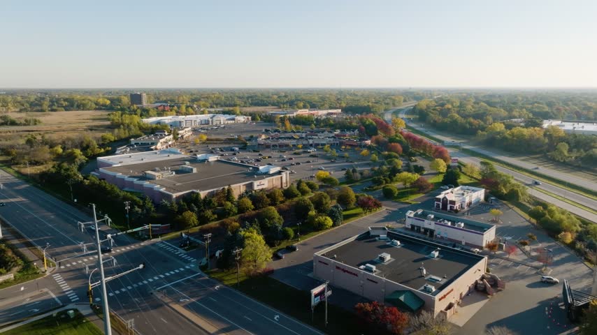 Aerial view of stores and a parking lot with fall foliage