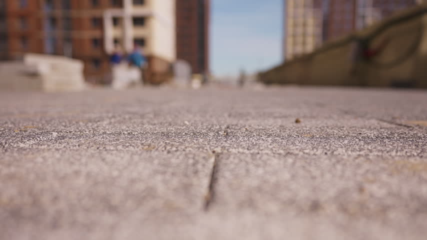 Close up of concrete sidewalk paving tiles with blurred buildings