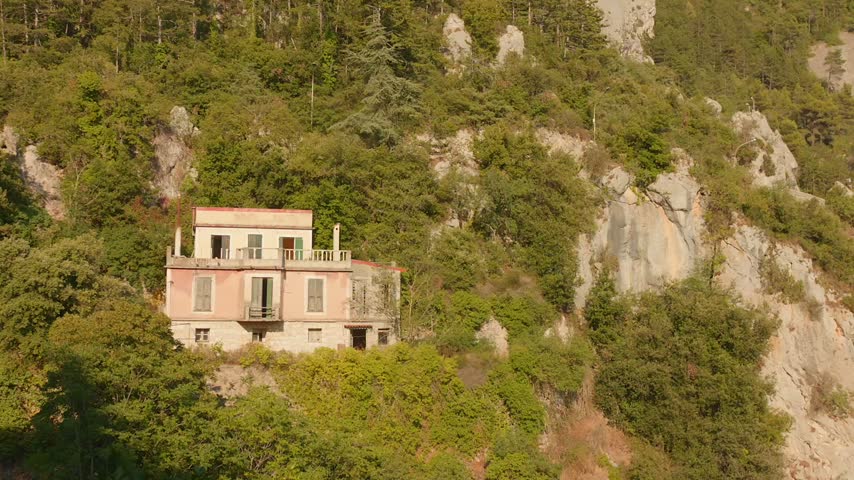 Old stone house nestled on a forested mountain slope in Peille, South of France