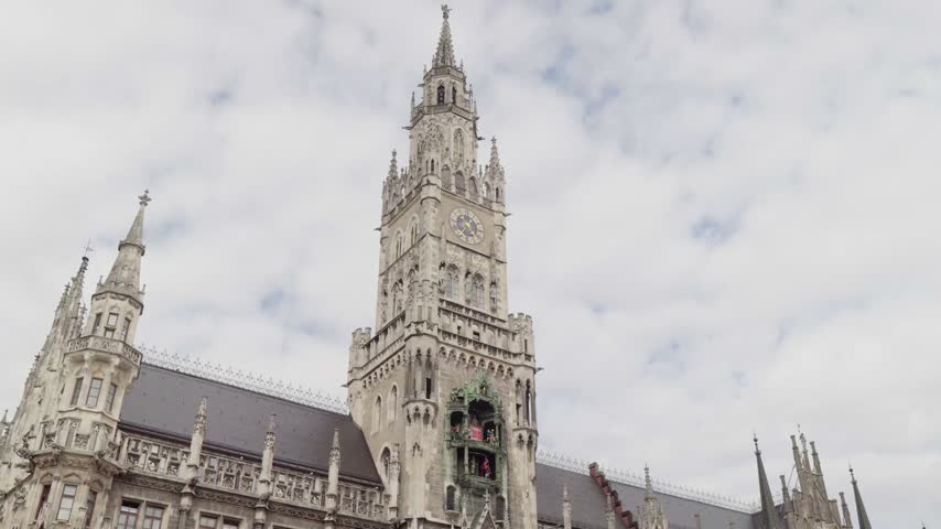 Hyper lapse view of Munich Town Hall showcasing intricate Gothic architecture ornate spires and detailed clock tower rising against a cloudy sky in Munich Germany