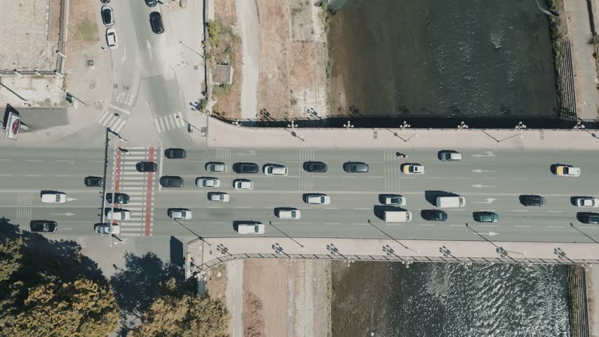 Cars driving on a bridge crossing a river in an urban city drone shot.