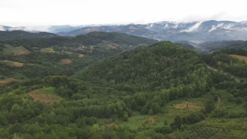 Drone aerial panning over a road on a green mountain in Western Serbia on a cloudy day