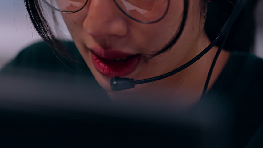 Woman Wearing Glasses and Headset, Speaking into Microphone During Customer Service Call Center Communication, Providing Focused Remote Support with Warm Smile in Close Up Portrait