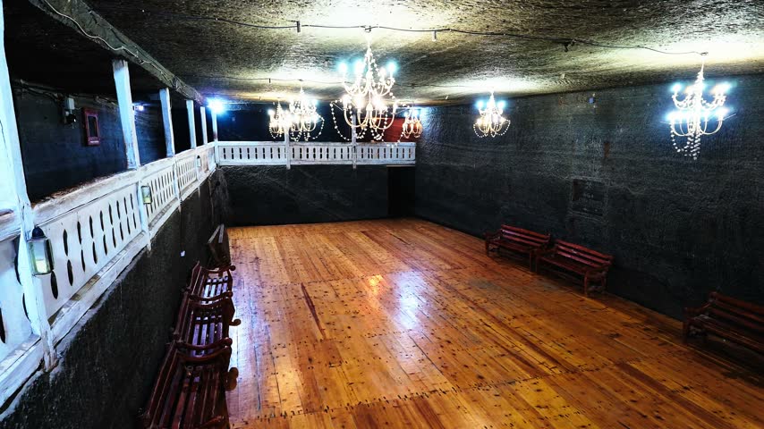 Interior of an underground visitor area at the historic Cacica salt mine, illuminated by artificial lighting.