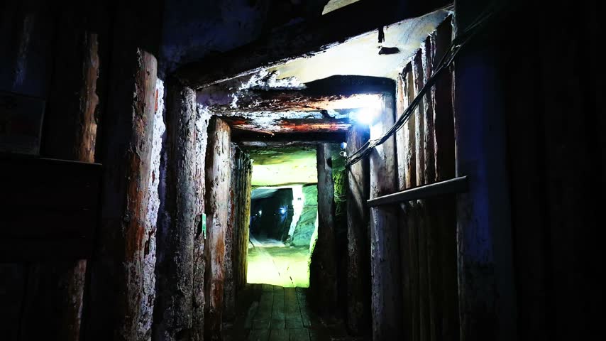 Narrow atmospheric corridor inside the historic Cacica salt mine, with illuminated passage leading deeper underground.