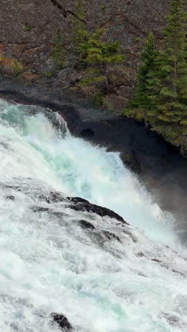 The powerful Bow Falls cascades over wide rock ledges on the Bow River at Banff National Park, Alberta, a scenic whitewater waterfall in the Canadian Rockies.