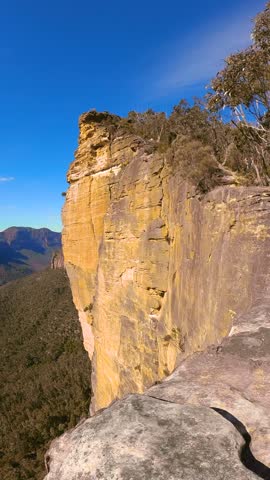 Slow motion vertical panning footage of sandstone cliffs and forested valleys from Baltzer Lookout at Hanging Rock, Blue Mountains, Australia.