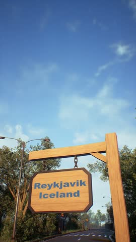Airplane flying in the blue sky above a wooden welcome sign reading Reykjavik, Iceland