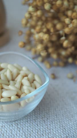 Pine nuts in a bowl on a table with dried flowers