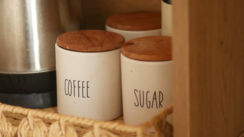 Coffee and sugar jars on wooden shelf in kitchen
